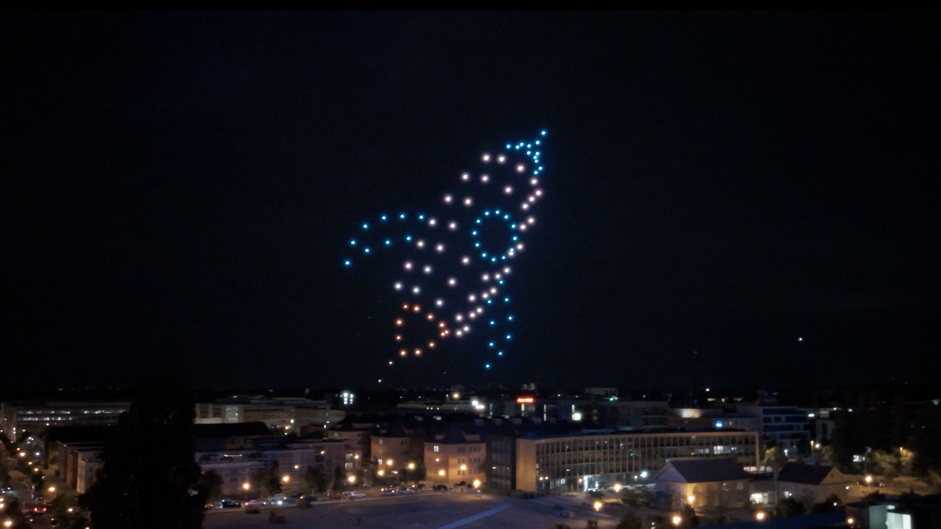 Eine Drohnenshow zeigt eine Rakete in der Luft.
