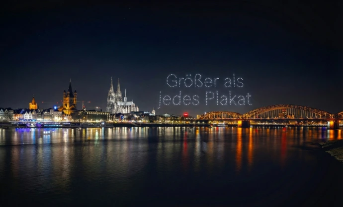Skyline von Köln - Drohnenshow schreibt "Größer als jedes Plakat" in den Himmel